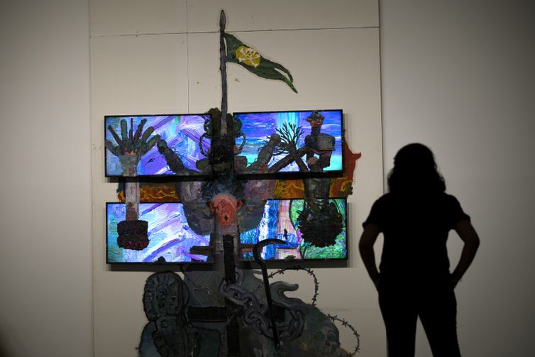 Joedson Alves/Agencia Brasil Brasilia 07/02/2023 - Uma mulher é vista em silhueta observando a obra sobre drywall e quatro monitores de TV da série Teatro Nagô Cartesiano. A cruz que penetra Pindorama, do artista, Thiago Martins de Melo, na Exposição Brasil futuro