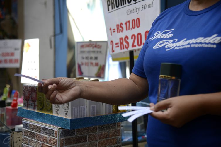 Vendedora entrega fragrâncias aos pedestres em loja na tradicional área de compras do Saara, no centro do Rio de Janeiro